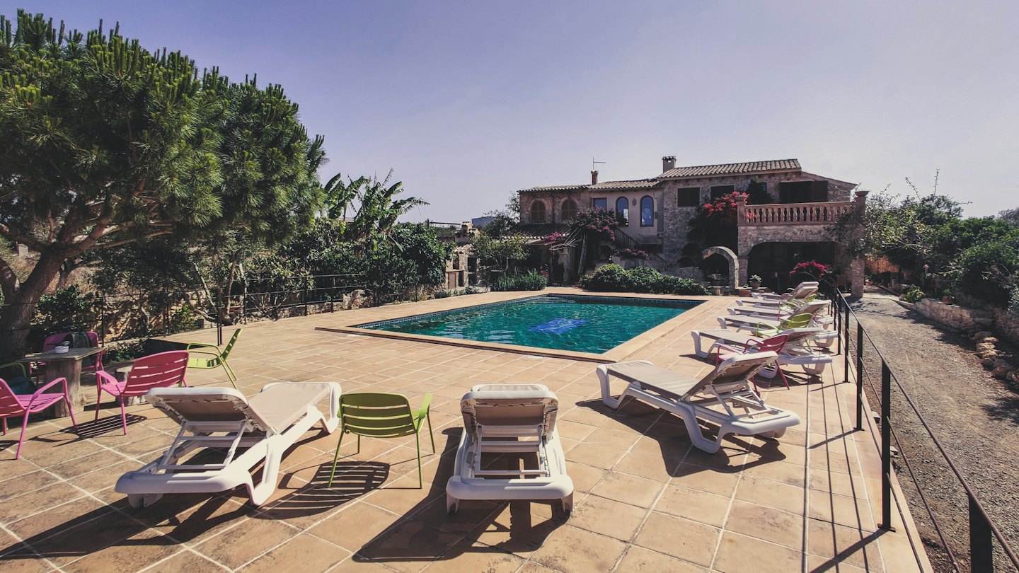 Stone villa pool area with lounge chairs and blue sky.