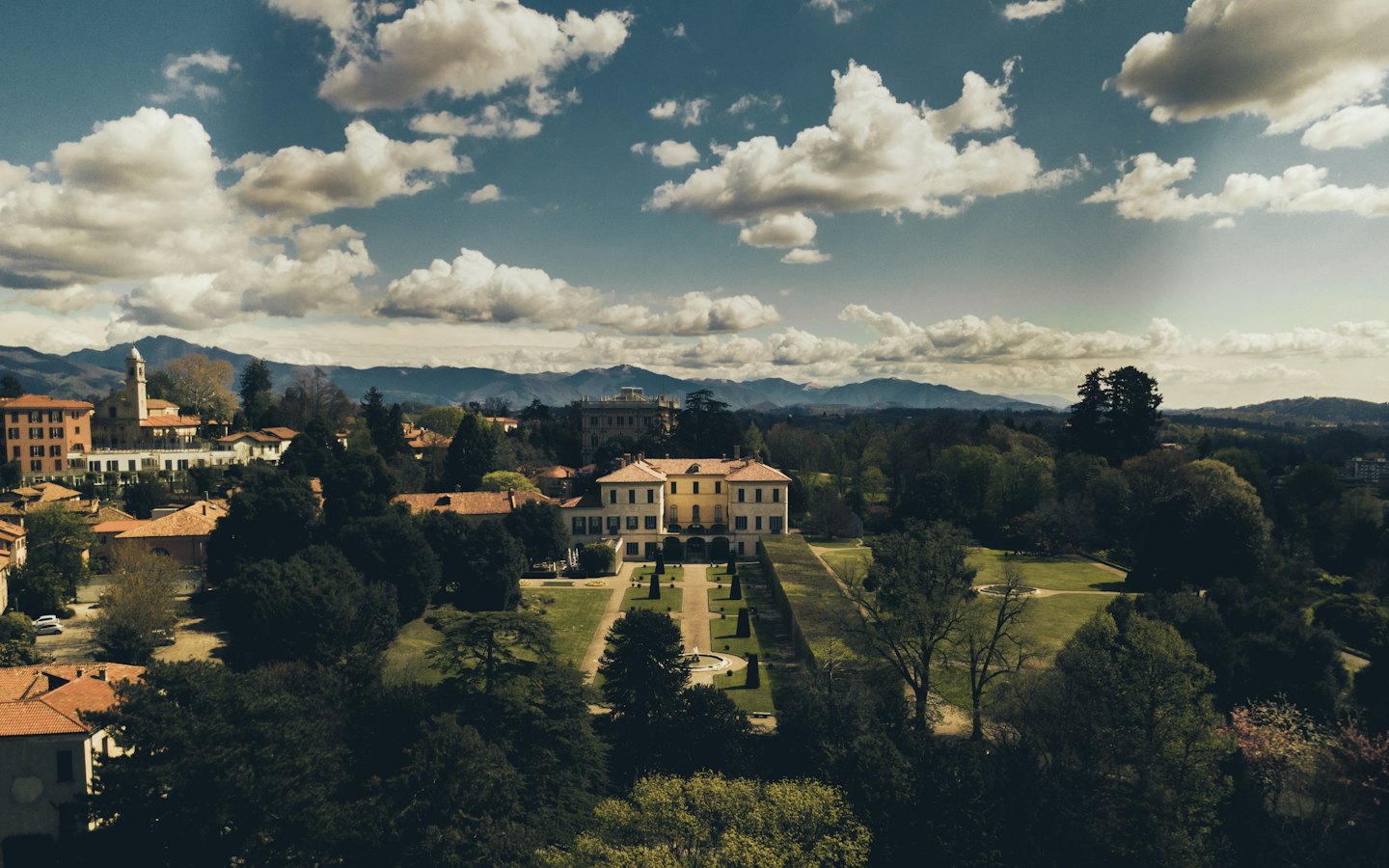 Grand cream villa overlooking a town with terracotta roofs.