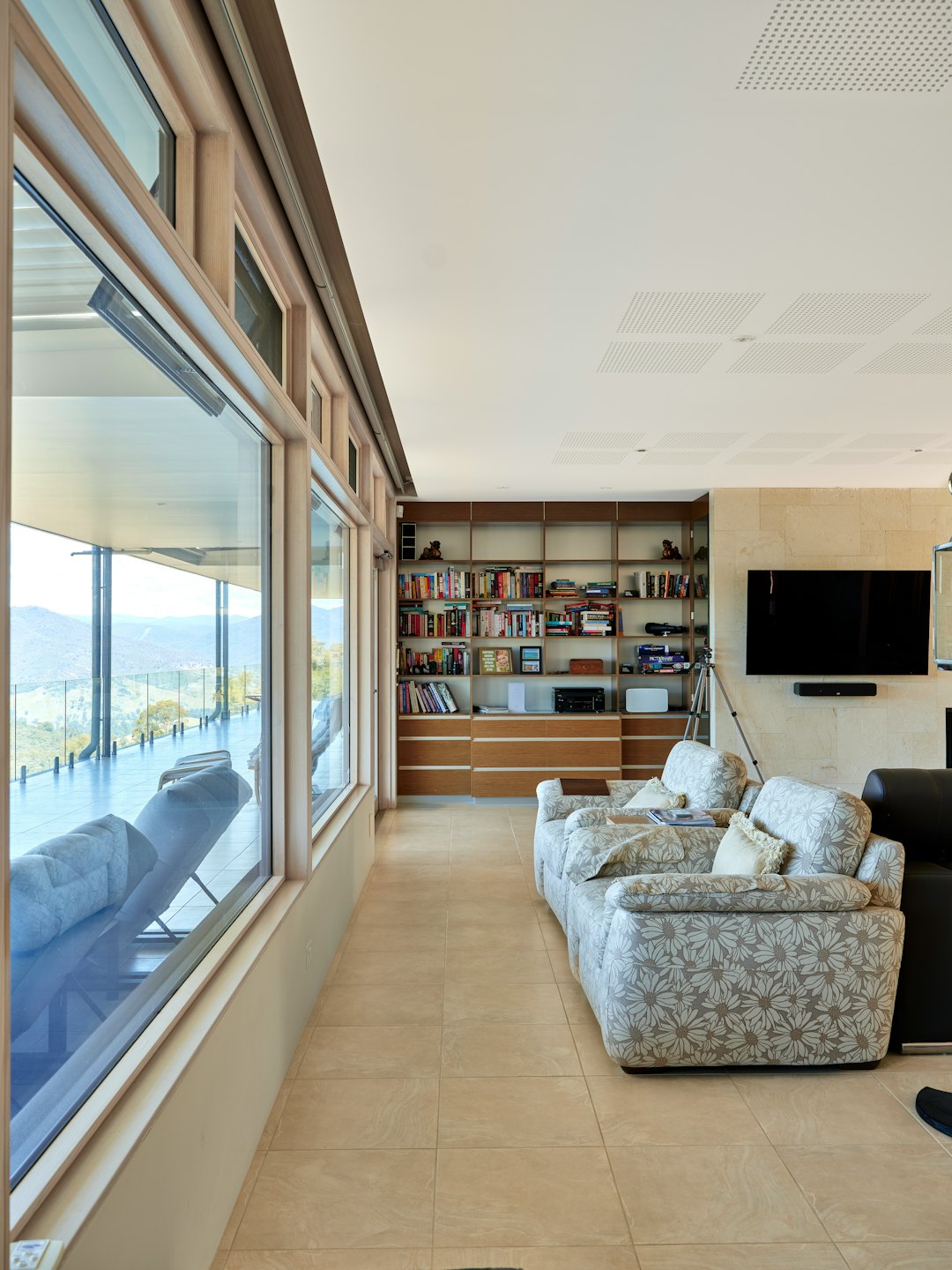 Modern living room with floral sofas and panoramic hill views.